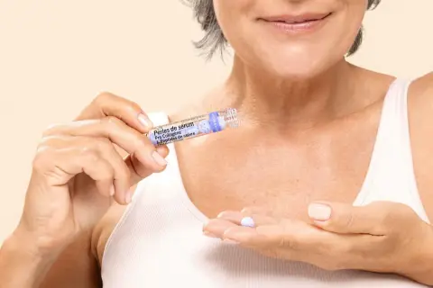 Une femme tient une perle de sérum contenant des peptides, prête à l'appliquer pour un soin anti-âge.