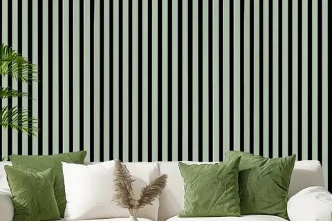 Grüne Kissen auf weißem Sofa vor vertikal gestreifter Wand. Akustikpaneele verbessern den Raumklang und die Ästhetik.