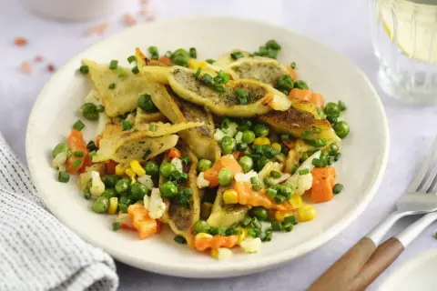 Gebratene Maultaschen mit Erbsen, Karotten und Mais, garniert mit Schnittlauch. Ein herzhaftes Gericht, das Lust auf mehr macht.