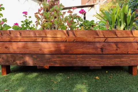Mesa de cultivo de madera con flores y plantas verdes. Ideal para aprender cómo hacer una mesa de cultivo.