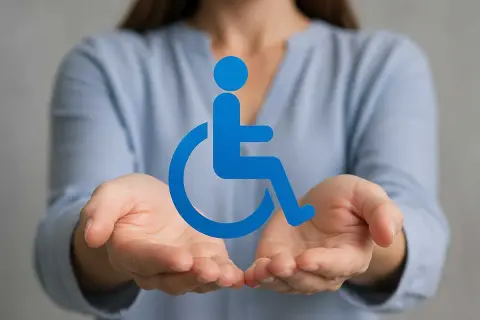 Hände halten ein blaues Rollstuhlsymbol. Nützliche Tipps für den Antrag auf Schwerbehinderung.