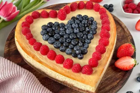 Herzförmiger Kuchen zum Muttertag, dekoriert mit Himbeeren und Blaubeeren. Ein süßes Dankeschön für Mama.
