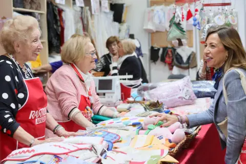 Sonríen vendedoras en el mercadillo Ozanam Zaragoza, mostrando textiles y peluches.