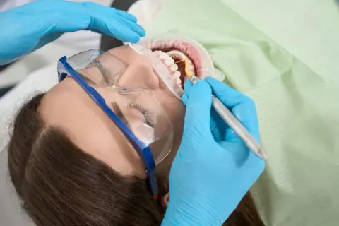 Dentysta wykonuje zabieg higienizacji zębów. Czas ten jest krótki, a efekt olśniewający.