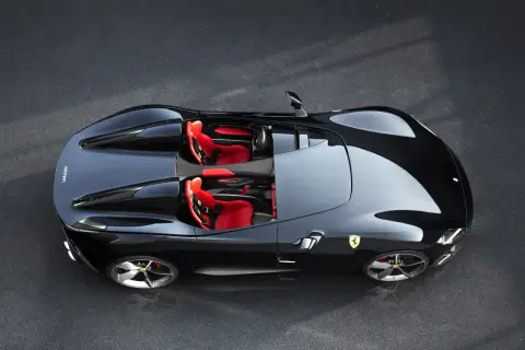 Czarny Ferrari Monza SP1 z czerwonymi siedzeniami, gotowy do jazdy po torze.