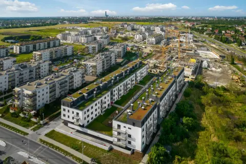 Nowe osiedle z zielonymi dachami, w tle budowa i miasto. Brak śladów powodzi.