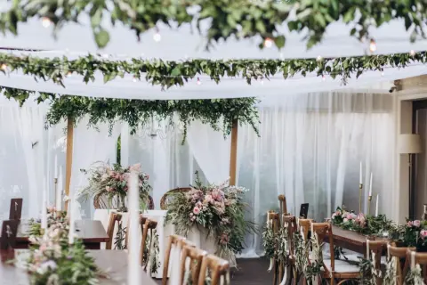 Udekorowane zielenią i kwiatami stoły tworzą magiczny styl boho na wesele. Delikatne tkaniny i girlandy dodają romantyzmu.