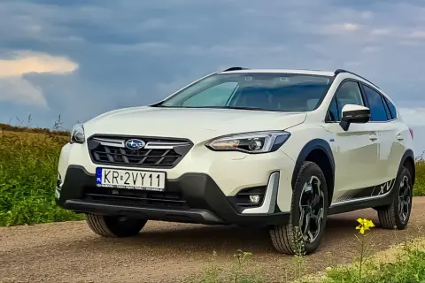 Biały Subaru XV na drodze polnej, z polami w tle. Rozważasz zakup? Sprawdź wady i zalety tego modelu.