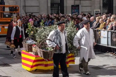 Hombres con trajes tradicionales desfilan en las fiestas Cuarte de Huerva, portando cestas con uvas y pan.