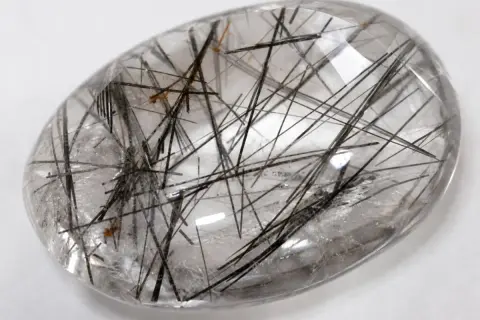 Cuarzo rutilado propiedades: piedra transparente con inclusiones negras y doradas, como un bosque de agujas.
