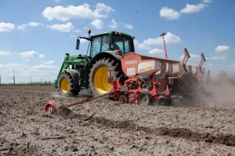 Traktor sieje na polu. Koalicja Obywatelska obietnice dla rolników a rzeczywistość – ciężka praca na roli trwa.