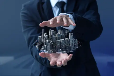 Biznesmen trzyma w dłoniach futurystyczne miasto, symbolizujące inwestycje w nieruchomości i rozwój **REIT**.
