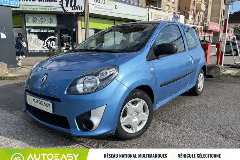 Une Twingo 2 phase 2 bleue, garée devant un commerce.