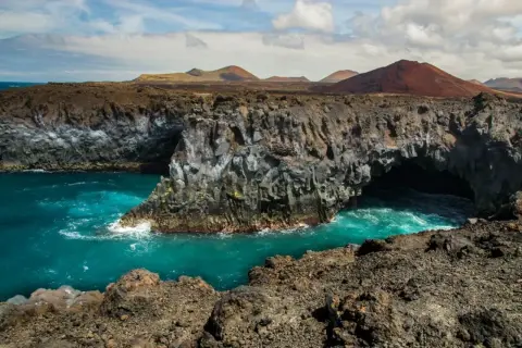 Acantilados volcánicos y mar turquesa en los Hervideros, Lanzarote. Un paisaje lunar con cuevas marinas.