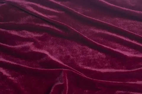 Głęboki, burgundowy rodzaj welwetu, miękko układający się w fałdy, odbijający światło.