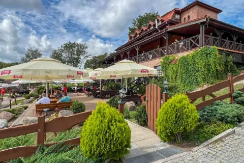 Odkryj najlepsze restauracje na Mazurach! Letni ogródek z widokiem na jezioro, gdzie można delektować się posiłkiem pod parasolami.