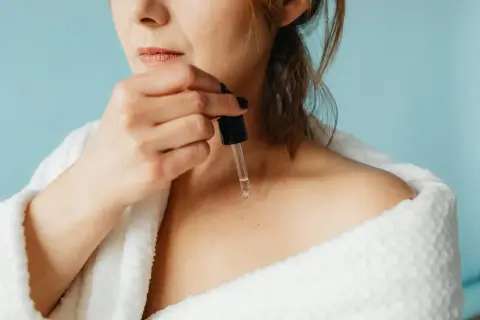 Frau trägt reines Retinol mit Pipette auf ihre Haut auf.