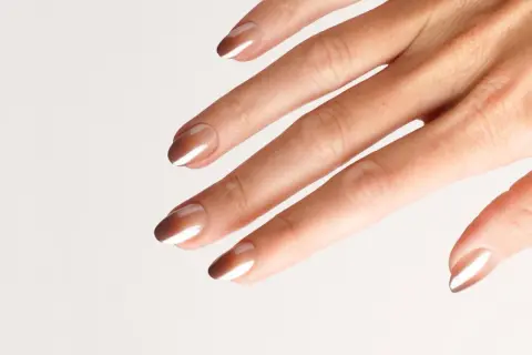 Eine Hand mit eleganten Nägeln im Ombre-Look, braun und weiß verlaufend.