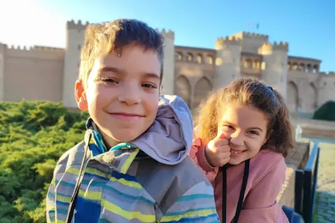 Dos niños sonríen frente a un palacio en Zaragoza. ¡Una aventura familiar en el museo!