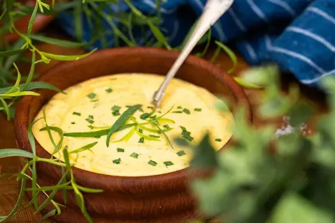 Krämig bearnaisesås i träskål, perfekt för ett enkelt bearnaisesås recept med stavmixer. Garnerad med färsk dragon.