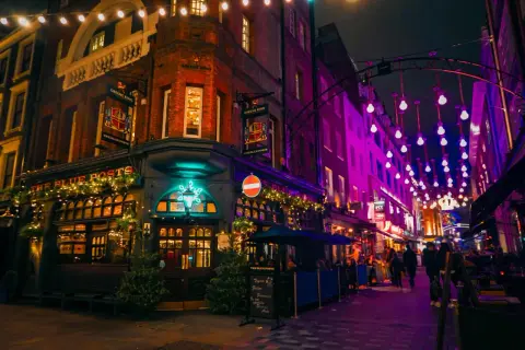 En livlig kväll i Soho, London, med The Blue Posts pub upplyst av julbelysning och neonskyltar.