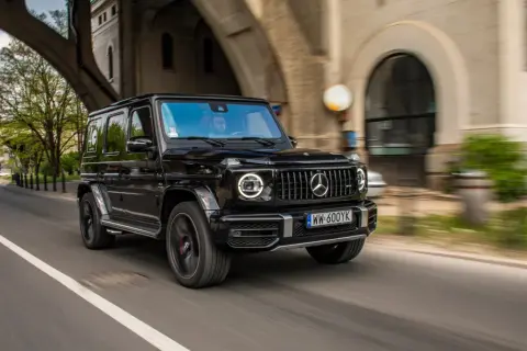 Czarny Mercedes G63 z okrągłymi światłami LED pędzi pod wiaduktem.