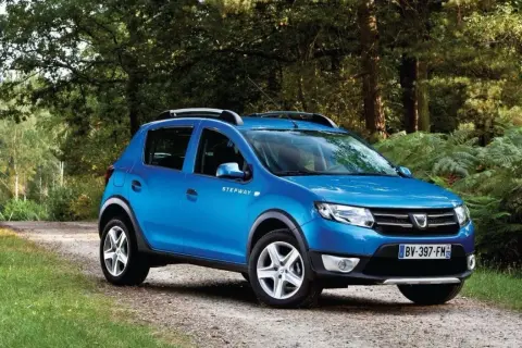 Niebieski Dacia Sandero Stepway na leśnej drodze, gotowy na przygodę.