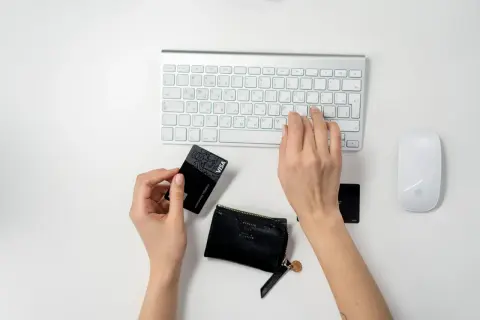 Ręce wpisują dane karty płatniczej na klawiaturze, przygotowując się do transakcji online. To pierwszy krok, jak zacząć sprzedawać w internecie.