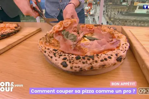 Une pizza al taglio généreuse, garnie de jambon cru et de basilic, est coupée avec des ciseaux. Un chef montre comment la découper comme un pro.