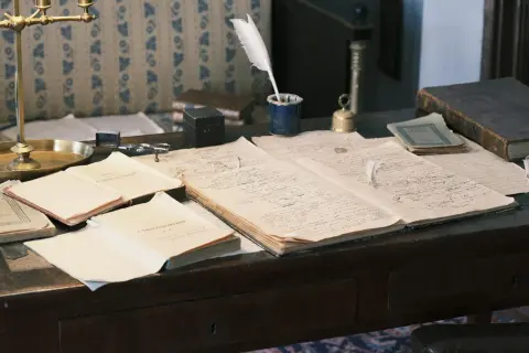 Bureau ancien avec des documents manuscrits, une plume, un encrier et un livre. Un aperçu de l'histoire familiale, peut-être des archives de geneafrance deces.
