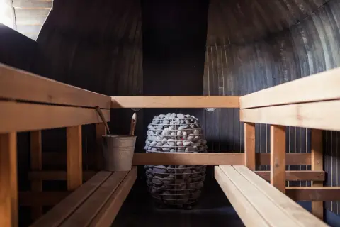 Drewniana sauna z kamiennym piecem. Czy sauna po treningu jest zdrowa? Odpoczynek i regeneracja po wysiłku.