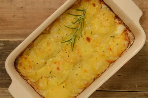 En gyllene pommes anna i en ugnsform, toppad med en rosmarinkvist. Perfekt till helgmiddagen.