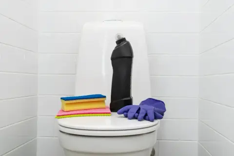Produits de nettoyage pour les toilettes : une bouteille de produit, des éponges et des gants violets. Une astuce de grand-mère pour détartrer les wc.