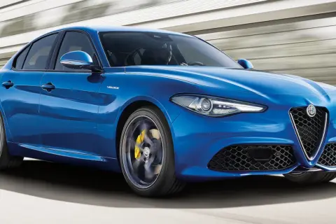 Błękitne Alfa Romeo Giulia Q4 Veloce w ruchu, z żółtymi zaciskami hamulcowymi i sportowym wyglądem.