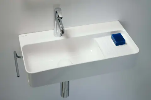 Elegancka, mała umywalka wisząca z chromowaną baterią i kostką niebieskiego mydła.