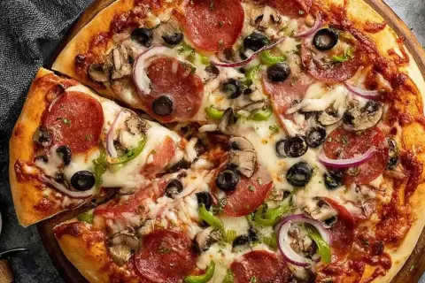Pyszna pizza z pepperoni, oliwkami, pieczarkami i cebulą, idealna na szybki obiad. Ciasto na proszku do pieczenia sprawia, że jest puszyste i chrupiące.