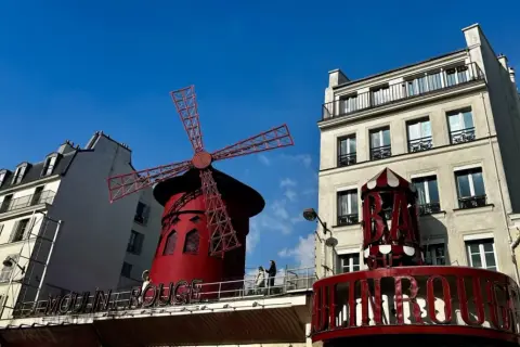 Słynny czerwony wiatrak Moulin Rouge na tle błękitnego nieba.