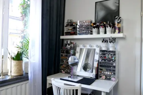 En perfekt smink ordning med genomskinliga förvaringslådor fyllda med smink och borstar. Ett sminkbord med spegel och lampor.
