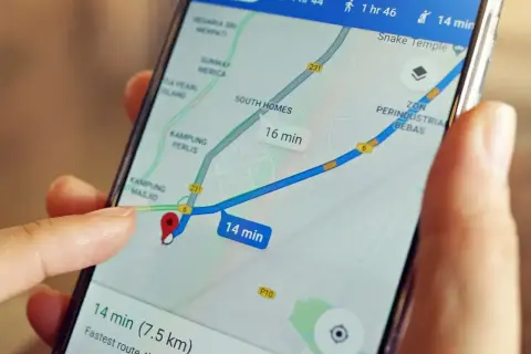 Palec dotyka ekranu smartfona z mapą, pokazując trasę i czas dojazdu. Dowiedz się, jak wysłać pinezkę, by udostępnić lokalizację.