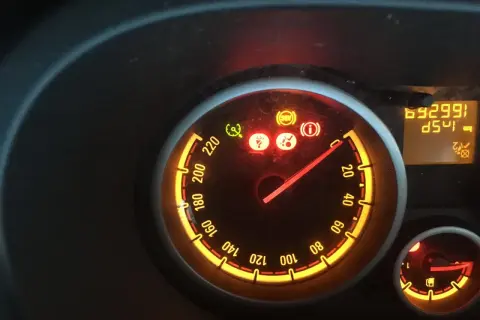 Tableau de bord allumé, voyant ceinture de sécurité rouge, ABS et information activés. Le compteur affiche 69299 km.