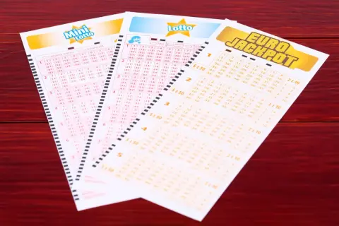 Kupony lotto: Mini Lotto, Lotto Plus i Eurojackpot na drewnianym tle.