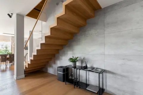 Nowoczesne schody dywanowe z drewna dębowego, szklana balustrada i beton architektoniczny tworzą elegancką przestrzeń.