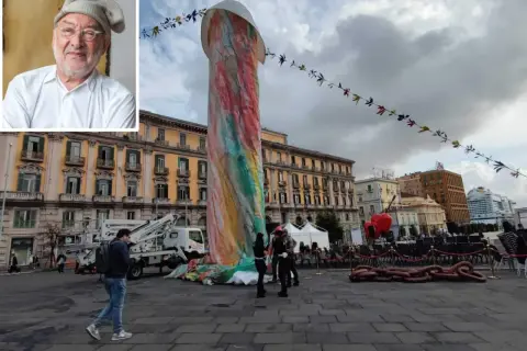 Ritratto di artista con inquadratura di una colorata statua di Pulcinella a Napoli, in piazza, con edifici storici sullo sfondo.