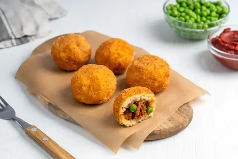 Arancini co to? Złociste kulki ryżowe, chrupiące na zewnątrz, z pysznym nadzieniem mięsnym i groszkiem w środku.