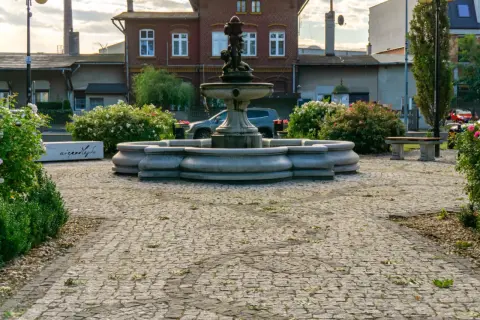 Kamienna fontanna i ławka w otoczeniu kwitnących krzewów róż tworzą urokliwy zakątek, jakby z najładniejszej wsi w Polsce.