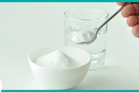 Un cucchiaino di bicarbonato pronto per essere sciolto in un bicchiere d'acqua. Un rimedio casalingo per diversi usi.