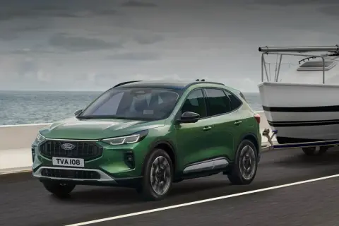 Zielony Ford Kuga z przyczepą i łodzią, idealny na wakacyjne wypady. Sprawdź ford kuga cena!