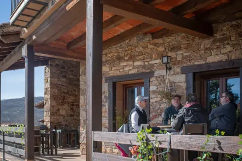 Gente disfrutando en la terraza de uno de los restaurantes de Horcajuelo de la Sierra, con vistas a la montaña.