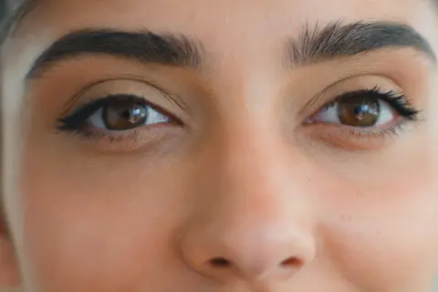 Zbliżenie na oczy kobiety z makijażem typu foxy eyes. Wyraziste brwi i subtelna kreska podkreślają spojrzenie.
