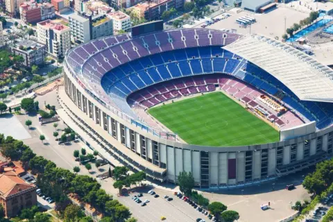 Widok z lotu ptaka na stadion Barcelony, z zieloną murawą i niebiesko-bordowymi trybunami.